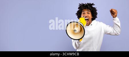 Agitated black teenager shouting into megaphone over violet studio background Stock Photo