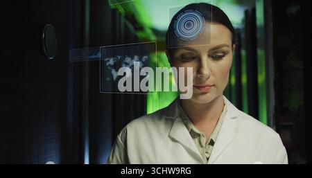 Monitoring female IT engineer using holographic displays on server racks in server room, copy space Stock Photo