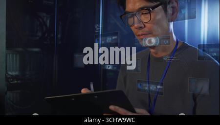 Korean technician monitoring server racks in server room, with tablet stylus and holograms Stock Photo