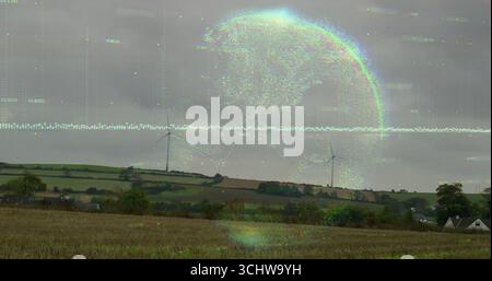 Hovering digital globe overlaying streaming code lines over harvested farmland, with wind turbines Stock Photo