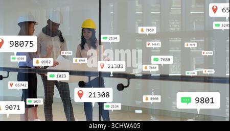 Reviewing team wearing safety helmets discussing blueprint on glass railing, atrium, floating icons Stock Photo