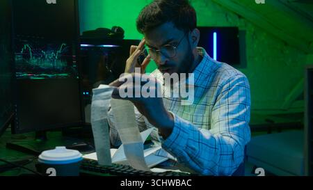 Arabian Indian man male guy programmer examining writing binary code coder freelancer engineer worker IT specialist monitor analyzing computer Stock Photo