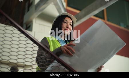 Korean Chinese business woman holding blueprint smiling businesswoman Japanese Asian female building construction plan project satisfied builder happy Stock Photo