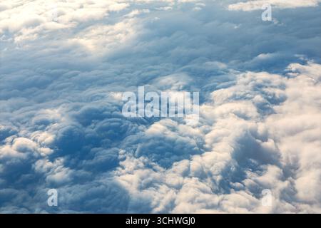 Layered clouds unfolds from above, revealing soft billows in shades of white, gray, and blue. Dramatic texture and shifting light create a mesmerizing Stock Photo