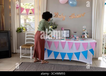 Decorating baby shower table, woman arranging cupcakes and colorful banners, at home Stock Photo
