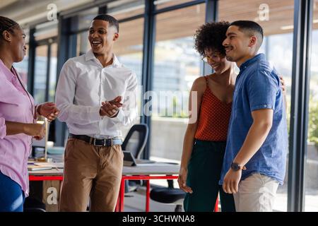 Colleagues laughing and chatting in modern office, enjoying team bonding moment Stock Photo