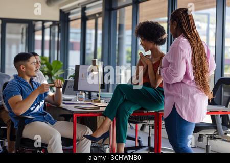 In office, diverse colleagues discussing project, smiling and engaging enthusiastically Stock Photo