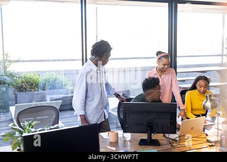 Team collaborating on project at office, using laptops and discussing ideas Stock Photo