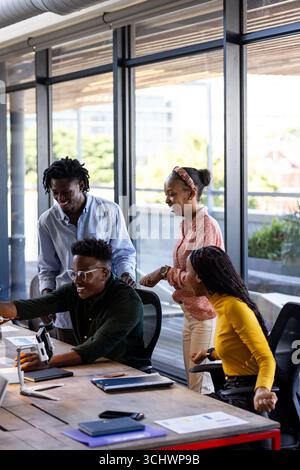 In office, team collaborating using digital devices, sharing ideas enthusiastically Stock Photo