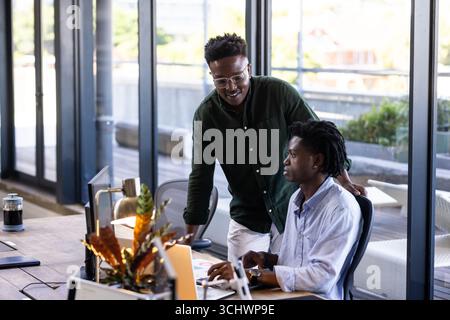 Collaborating in modern office, two men discussing project on laptop screen Stock Photo