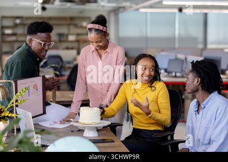 Team collaborating in modern office, discussing project while enjoying cake together Stock Photo