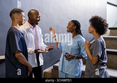Discussing patient care, African American medical professionals smiling in hospital hallway Stock Photo