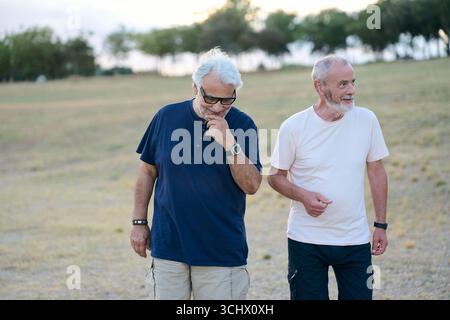 Two senior men walking and talking in a park Stock Photo