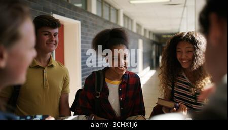 Happy people, students and laughing for funny joke, humor and recess together in school corridor. Teenager, group and friends with smile for social Stock Photo