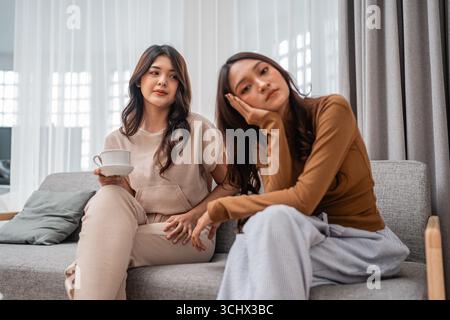 Two Young Women Relaxing Together in a Stylish Modern Living Room Setting Stock Photo
