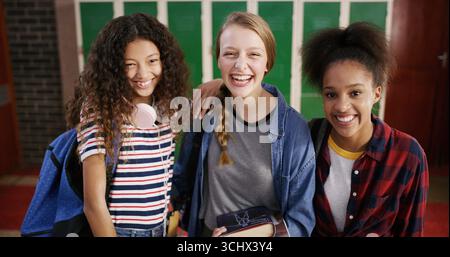 High school students, girls and happy in hallway for education, learning break or scholarship. Teenager portrait, friends and smile with textbooks for Stock Photo