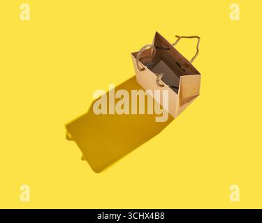 Open brown paper bag with shadow on bright yellow background minimalist composition. Stock Photo