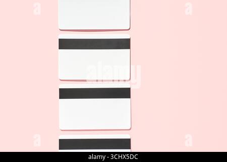 Blank white cards with black magnetic stripes on pink background positioned vertically. Stock Photo