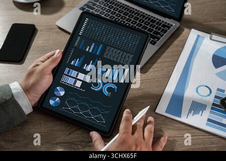 Businessman analyzing financial data and statistics on digital tablet with charts and graphs, concept of analytics, big data, business intelligence, a Stock Photo