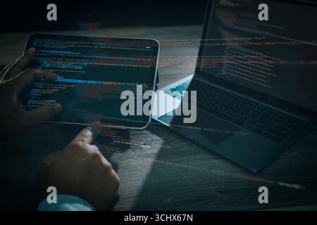 Programmer coding software on tablet and laptop with glowing lines of code, concept of programming, web development, cybersecurity, data technology, a Stock Photo
