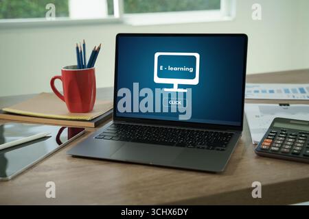 Laptop screen showing e-learning concept on desk with tablet, calculator, and stationery, representing online education, digital learning, and modern Stock Photo