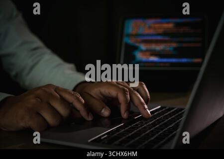 Close-up of programmer typing code on laptop with blurred screen of programming in background, concept of coding, software development, IT, cybersecur Stock Photo