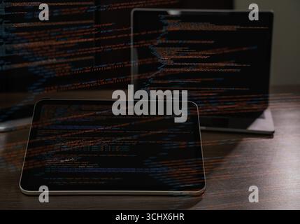Programmer workspace with source code displayed on multiple devices, concept of software development, IT engineering, coding, and data security techno Stock Photo
