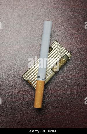cigarette and gold lighter on wooden table Stock Photo