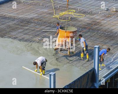 Workers pouring concrete on a construction site with concrete mixer and steel frame structure in the background, car park construction, Calw, Germany Stock Photo
