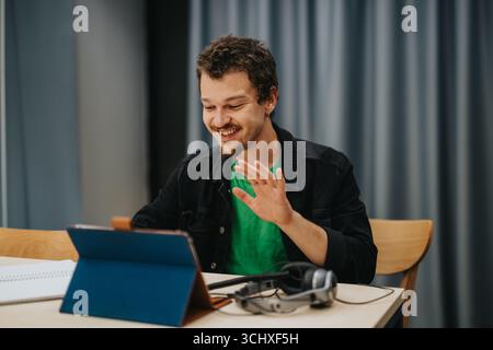 Young man joyfully engages in an online video chat with a tablet Stock Photo