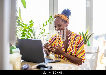 Smiling woman using laptop while sitting at desk in office Stock Photo