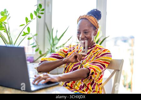 Smiling woman using laptop while sitting at desk in office Stock Photo