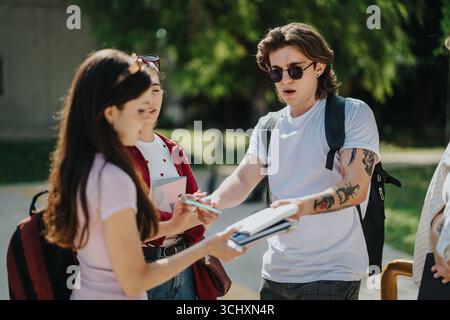 Group of students collaborating outdoors on a school project on a sunny day Stock Photo