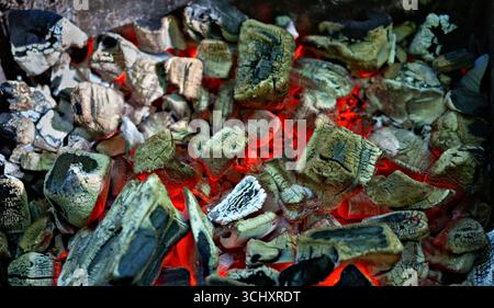Close-Up of Glowing Red Hot Charcoal Embers.Burning charcoal embers glowing red and black, captured in detail with textures and heat radiating from th Stock Photo
