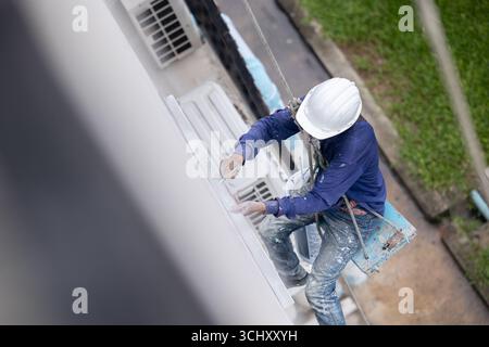 Exterior paint and leak repair technician builder, rope rappelling to repair buildings outside crack wall repainting and fix water leakage Stock Photo