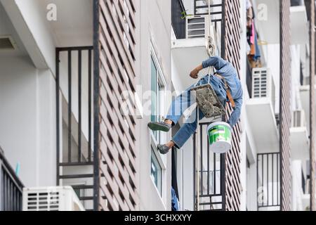Exterior paint and leak repair technician builder, rope rappelling to repair buildings outside crack wall repainting and fix water leakage Stock Photo