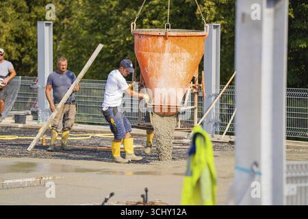 Construction workers unloading concrete with a large hopper on a building site with metal structures, car park construction, Calw, Germany Stock Photo