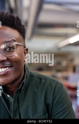 Smiling man in glasses wearing green shirt at modern office workspace Stock Photo