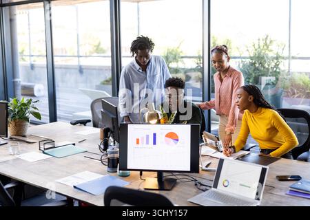 Team collaborating on project, analyzing data on computer screens in modern office Stock Photo