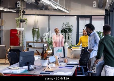 Diverse team collaborating in modern office, discussing project with enthusiasm Stock Photo