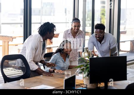 Collaborating in office, team enthusiastically working together around computer Stock Photo