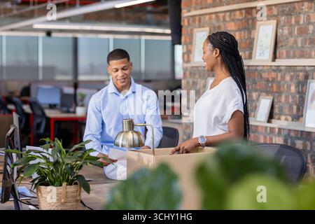 Colleagues in office unpacking box, discussing new project with enthusiasm Stock Photo