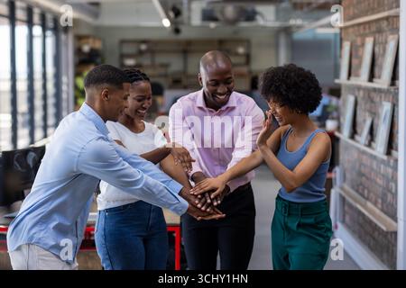 Diverse team in office celebrating success with hands together, smiling joyfully Stock Photo