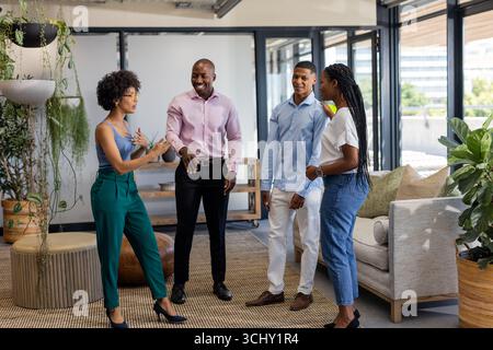 Colleagues in office discussing project, smiling and engaging in lively conversation Stock Photo