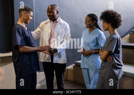 Discussing patient care, African American medical team collaborating and smiling at hospital Stock Photo