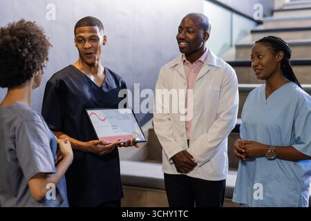 Discussing award certificate, medical professionals smiling and engaged in hospital hallway Stock Photo