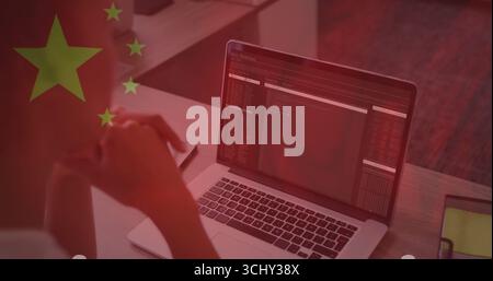 Typing Asian woman wearing shirt coding on silver laptop at home desk, with Chinese flag overlay Stock Photo