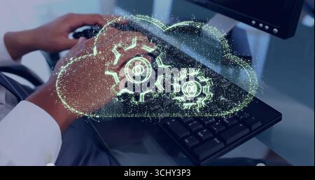 Showing worker wearing shirt typing on keyboard at office desk, with holographic cloud gear icon Stock Photo