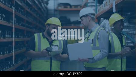 Workers in vests and helmets scanning inventory using scanner, checking on tablet in storage aisle Stock Photo