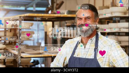 Standing man wearing shirt, apron in pottery studio with shelves floating digital icons, copy space Stock Photo
